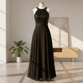 Woman wearing a black evening gown with sequin top in a fitting room.