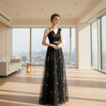 Woman wearing a black evening gown with floral embroidery on a white background